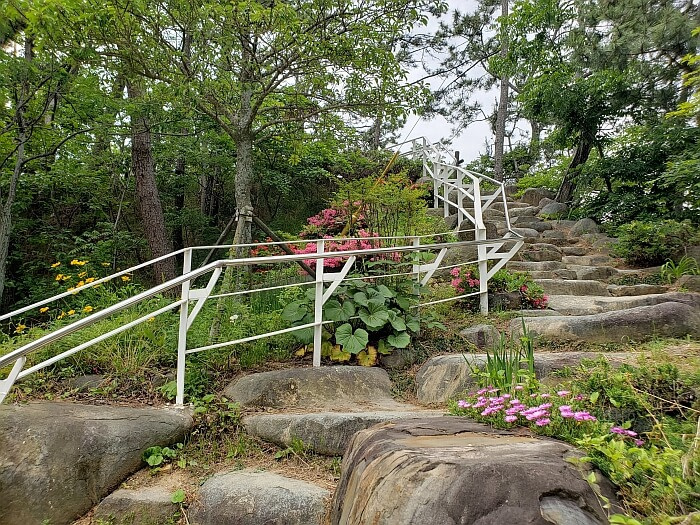 Stone stairs leading up to a small island with flowers along a white metal railing