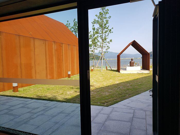 Ironclad ship structures in a courtyard with a statue of Je Jeong-gu facing Daega Reservoir in Goseong, Gyeonsangnamdo, Korea