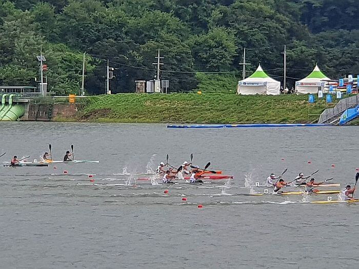 Canoes or kayaks finishing their race near the shore with tents