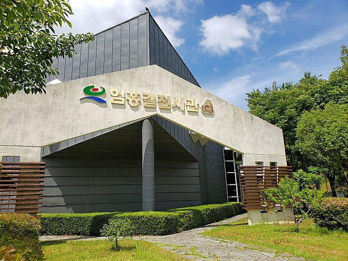 The front side of Eom Hong Gil exhibition hall museum with bushes and trees surrounding the building