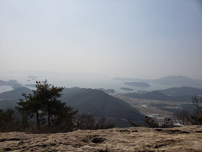 A large flat rock overlooking islands and peaks below
