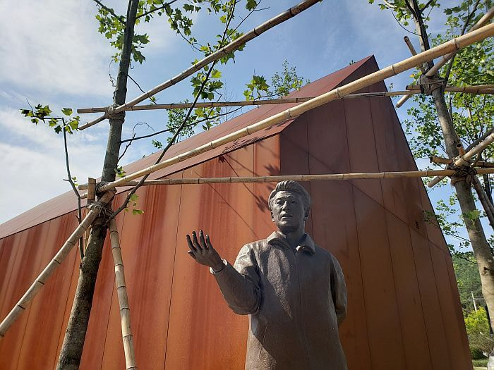Je Jeong-gu statue standing in front of steel structure with hand extended