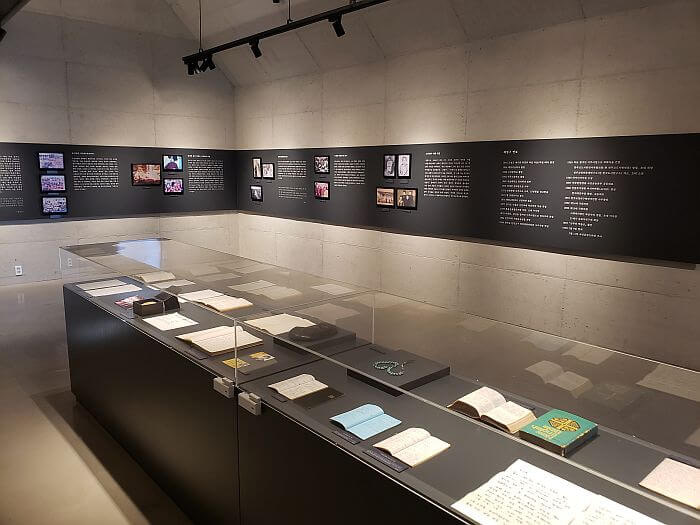 A memorial hall with some books and other items in the center of a room with graphics on the walls