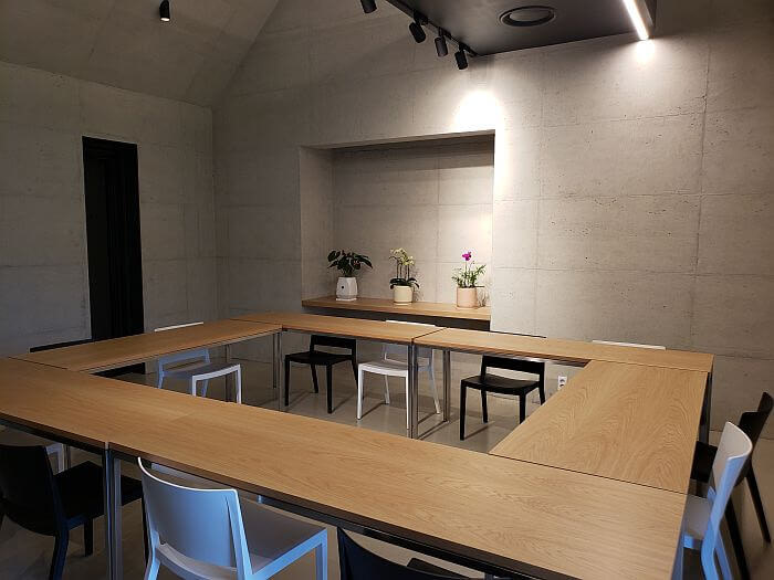 Tables arranged in a hollow square in a meeting room inside the steel structures