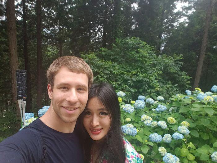 Nate and Alice in front of blue and white hydrangea flowers