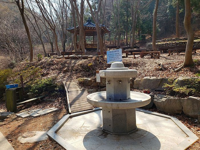 Natural water fountains next to some benches and a small pavilion