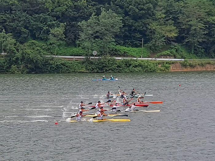 Paddlers in sync with their paddles racing alone the reservoir