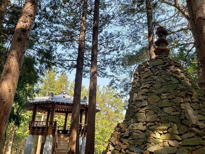 A structure of stacked rocks in the forest next to a pavilion