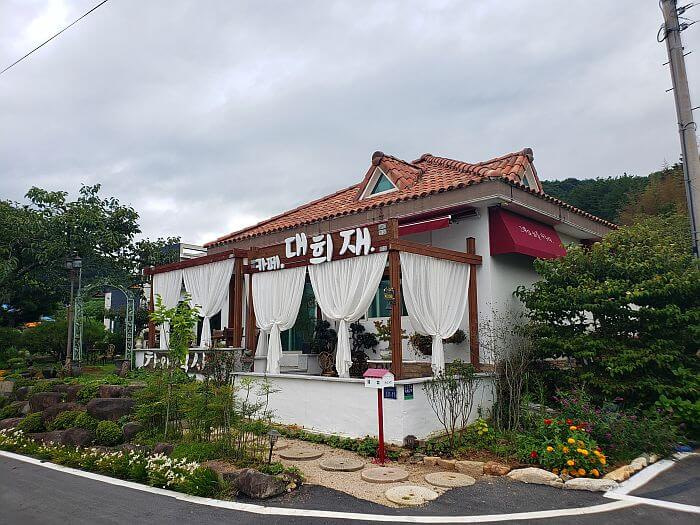 Exterior of Daehuijae Café with white curtains draped over an outside deck and flowers along the sides