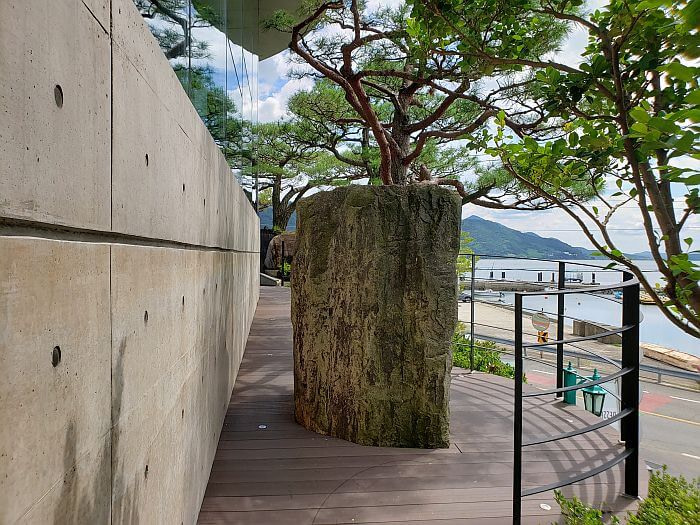 A large rock jutting out from the floor along the side of a building outside
