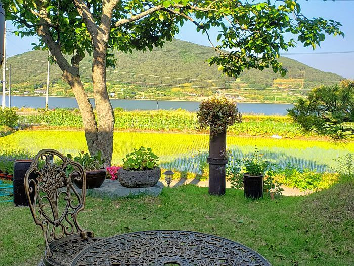 An iron table and chairs outside on grass looking out at Daega Reservoir and mountains
