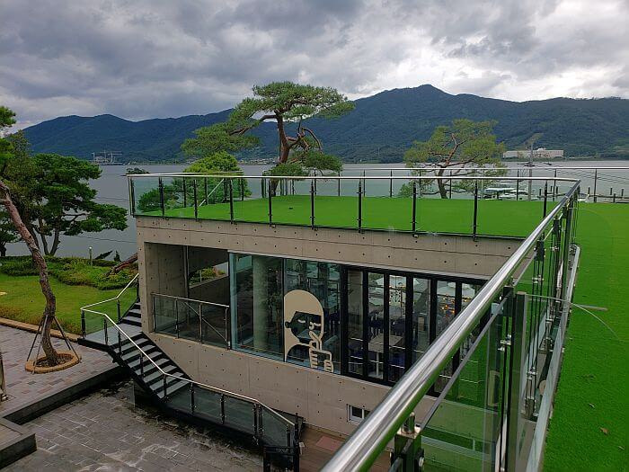 View of side of café building and rooftop with the sea and mountains beyond