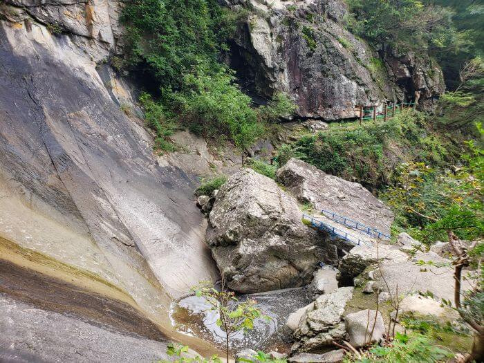 Waterfall down a sloped rock and small rock bridge