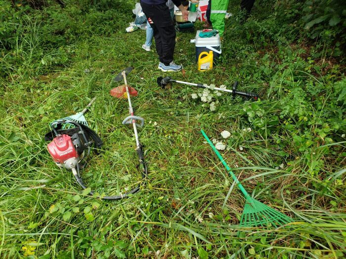 Weed whackers and rakes laying in the grass