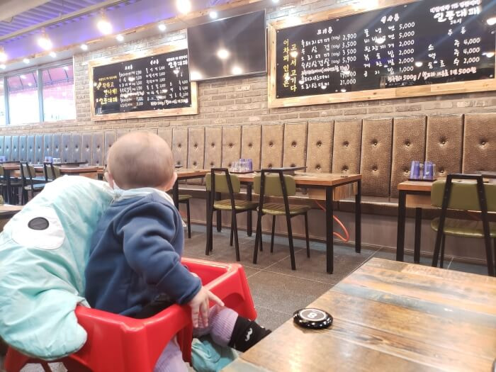 A baby sitting next to a call button on a table in a Korean restaurant