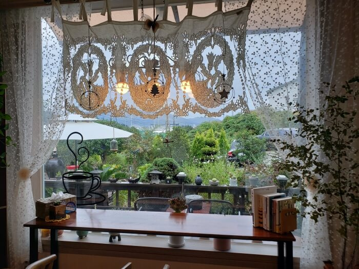 Elaborate doily hanging above a table next to a window and curtains