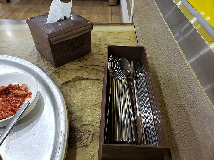 Metal chopsticks and spoons in a box on a table
