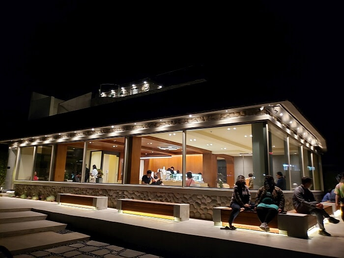 People sitting on benches at night outside a Korean café