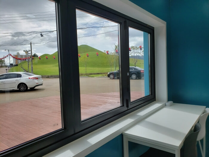 A table next to a window with a view of the ancient burial mounds in Goseong, South Korea