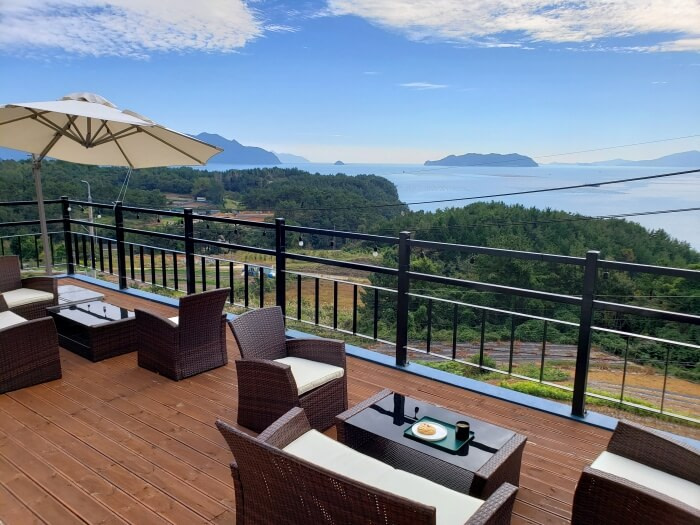 A tray of coffee and a pastry on a balcony table with a view of the sea