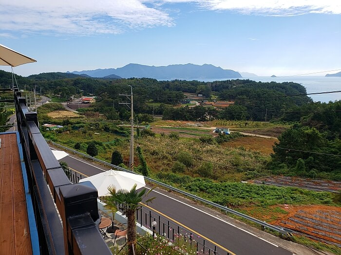 A view from a terrace of a countryside road in Korea with a nice café and not much else except for a nice sea view