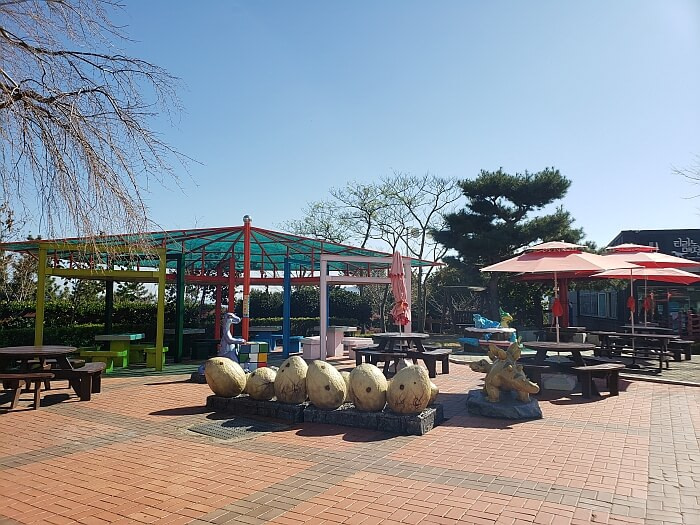 Covered picnic tables and dinosaur egg figures outside