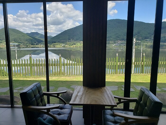 Cushiony chairs and table along a window viewing Daega Reservoir and mountains