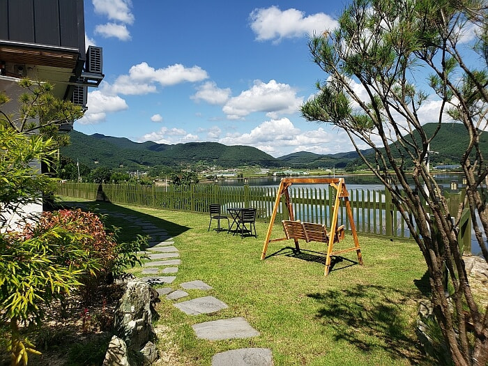 A swinging bench in the grassy yard of Daega Lake Café