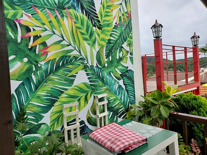 Some chairs next to a painted wall of banana leaves and others