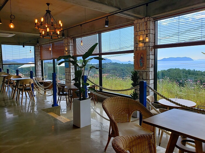 A row of tables and chairs along windows in The Wave Café facing the sea