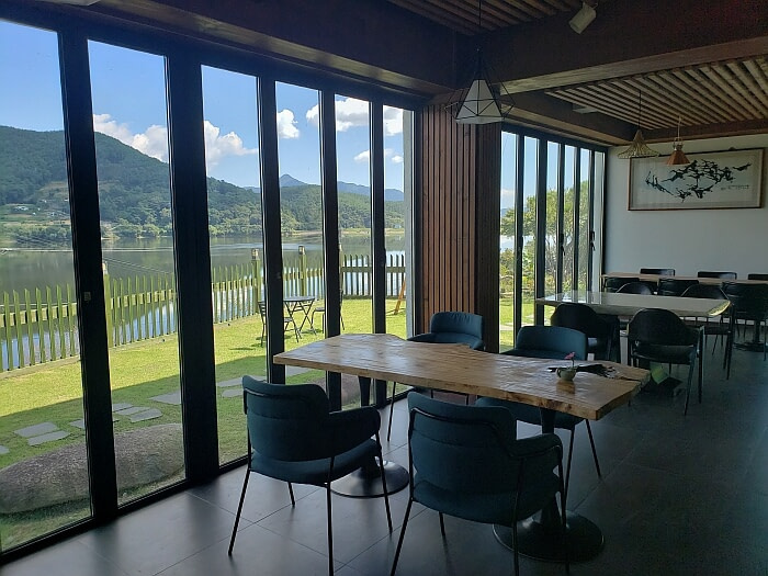 Tables in a cafe along a window overlooking Daega Reservoir in Goseong