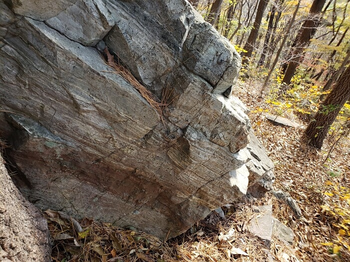 A large rock with multi-colored layers and lines and cracks visible