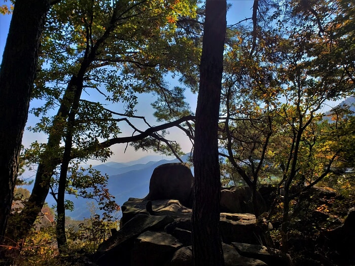 Rocks at a cliff edge in autumn with a view of many mountain peaks