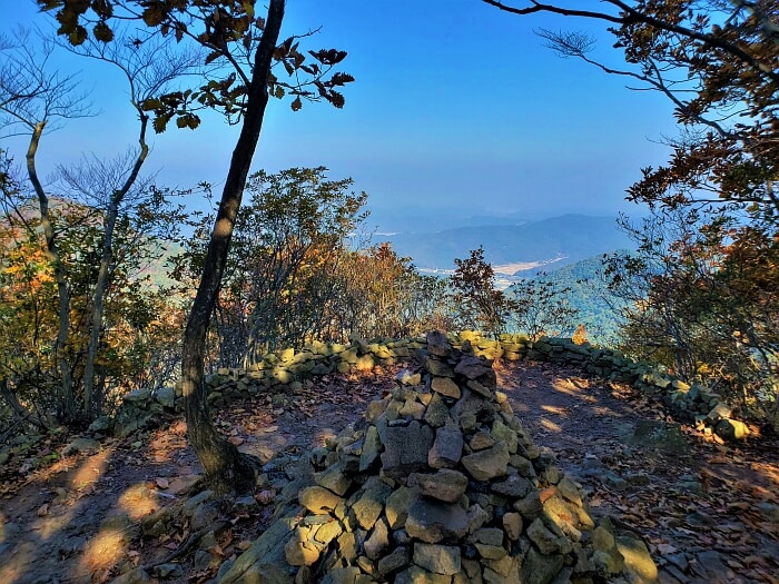 A pagoda of stacked rocks surrounded by a rock wall overlooking a mountainous view