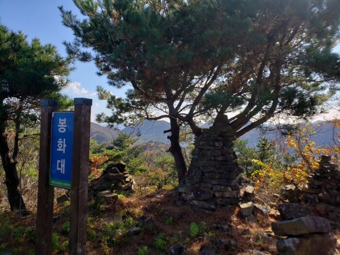 A beacon area with a sign overlooking other mountains