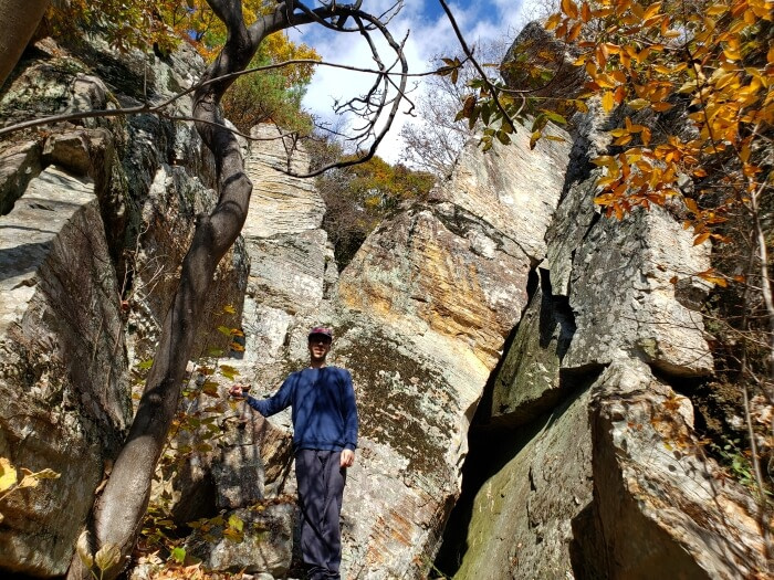 Nate standing next to large, leaning rocks at Yeonhwasan Park