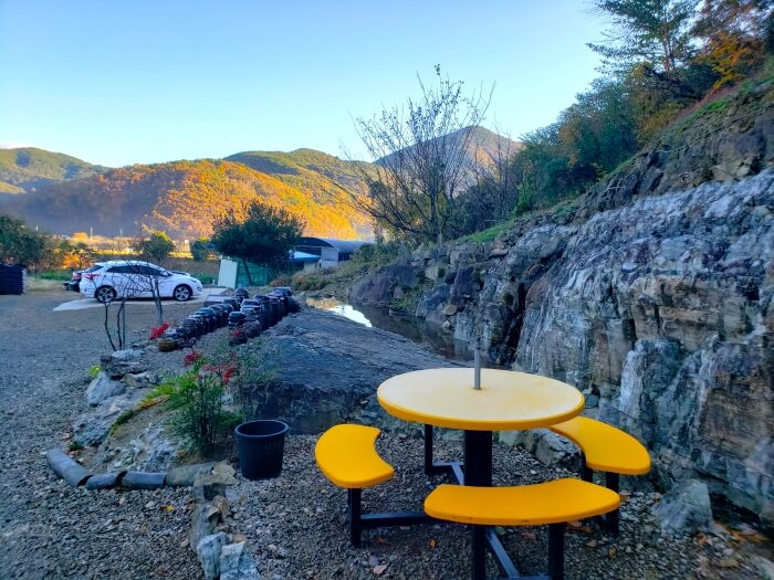 A picnic table outside next to rows of jars and rock