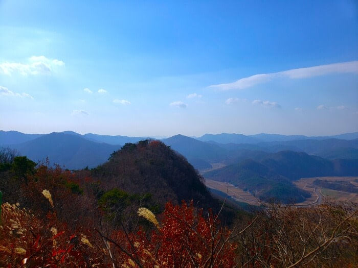 A smaller peak nearby with rice fields below