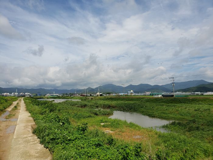A bike path along a river towards mountains and a town
