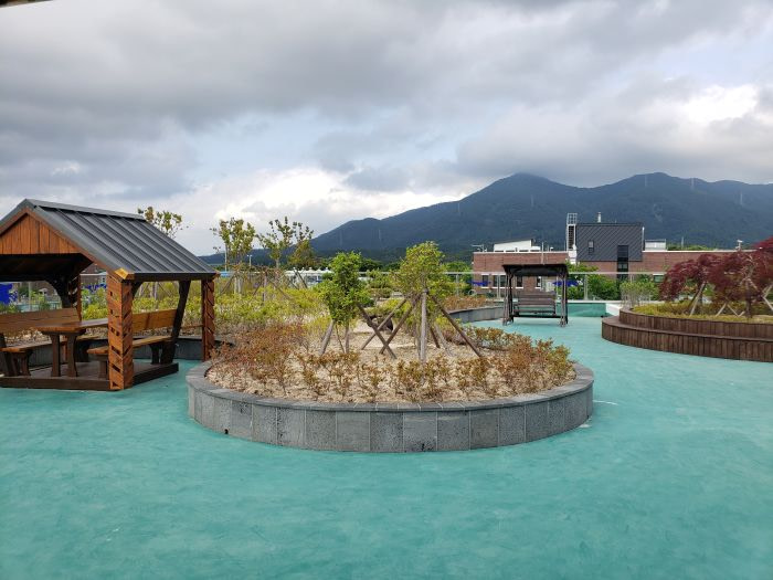 Picnic tables and a swinging bench on a rooftop with a mountain in the background