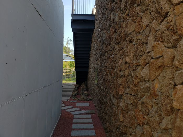 Stairs along a wall of rocks with a stone path between two walls