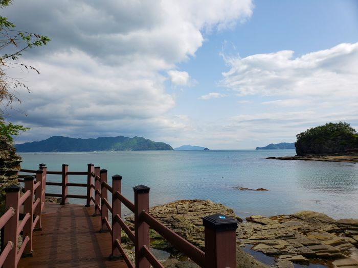 A coastal boardwalk at Sangjogam Park with turquoise blue water