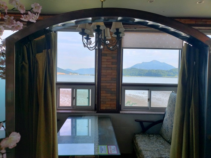 A booth with a curtain along a nice window with a view of the sea
