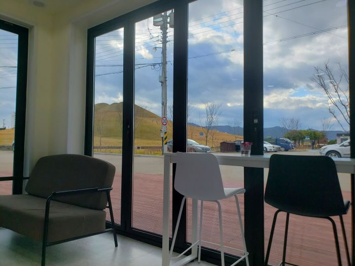 Cafe seating along a window overlooking large Songhakdong burial mounds