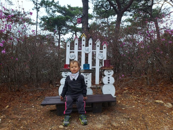 A toddler sitting at a set of three small figurine snowmen on Boli Island