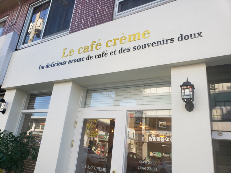 La Café Crème from outside with a clean white entrance and light posts