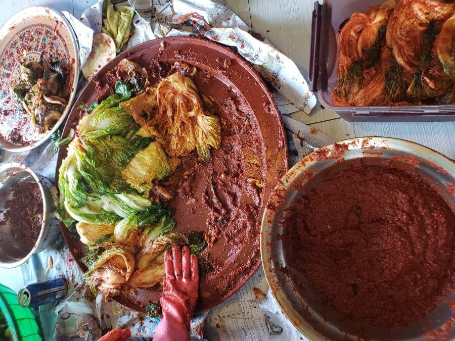 A large bowl of gochujang pepper sauce next to kimchi supplies for kimjang