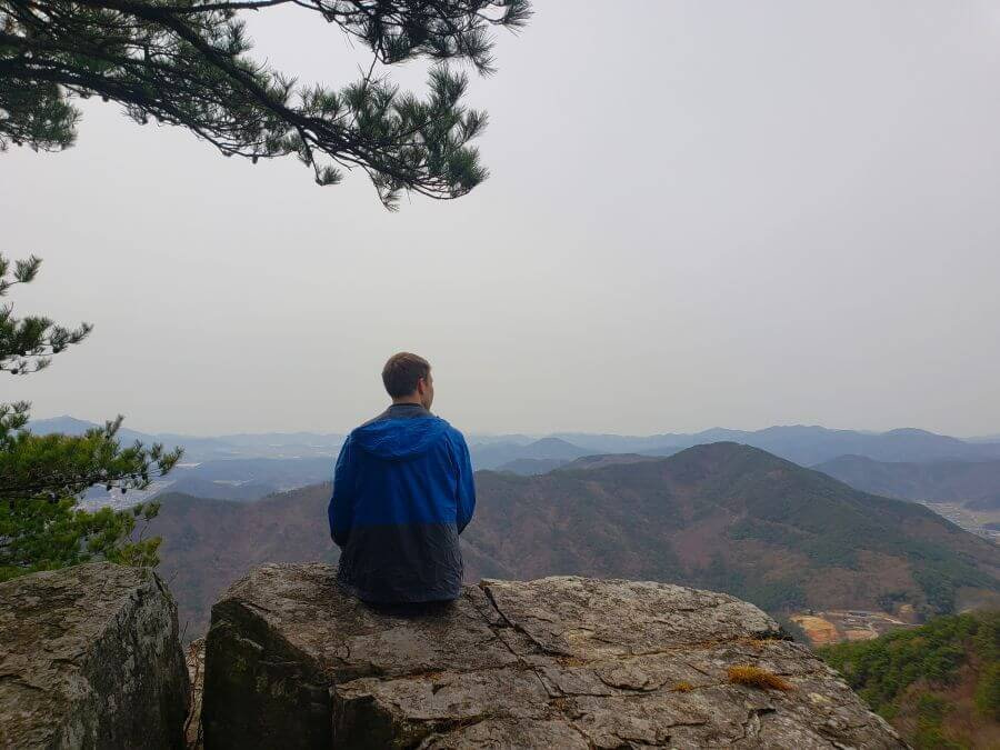 Nate sitting on a rocky ledge at Guksubong Peak