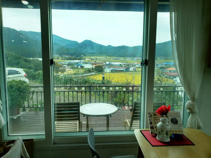 A table next to a deck and a window overlooking a village