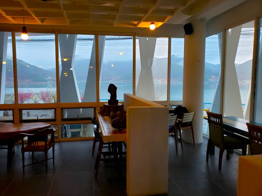 Seating in a cafes along windows and a view of the sea and mountains